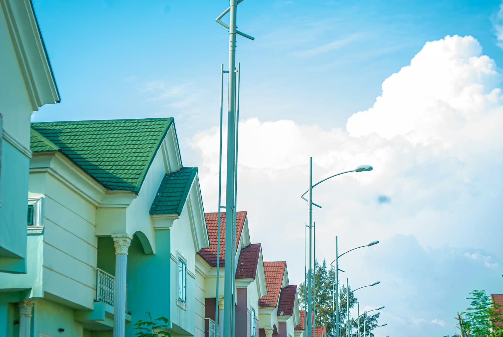 A row of finished houses with tiled roofs and columned porches on an estate street in Abuja