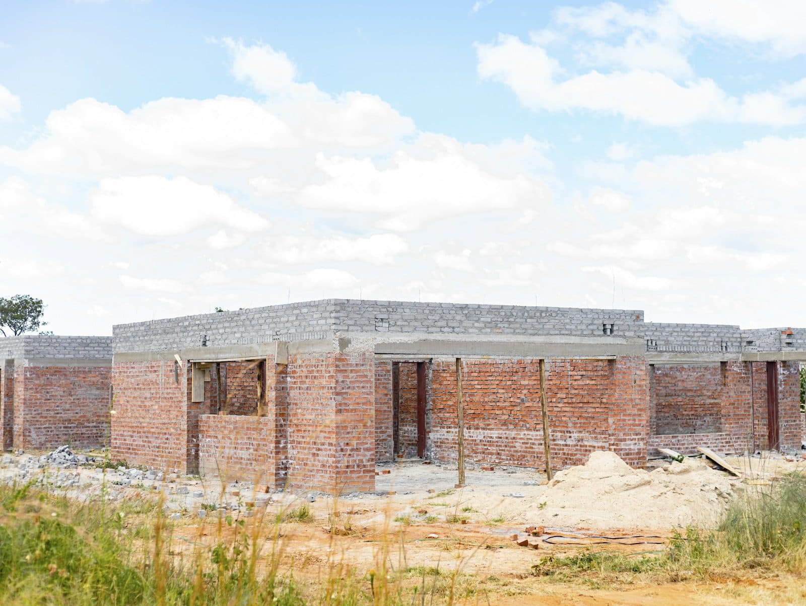 Front: walls at roof level, ring beam cast along the wall tops, timber props under the beams along the front. No roof timbers or sheets.