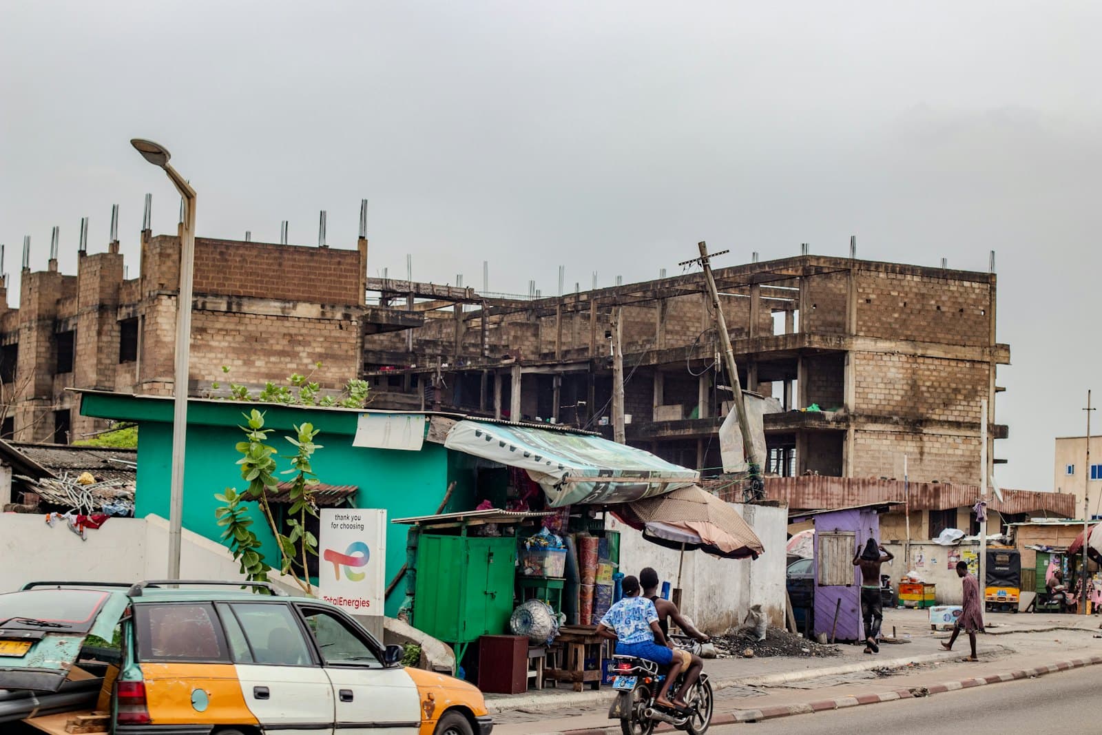A busy street with unfinished buildings and market stalls
