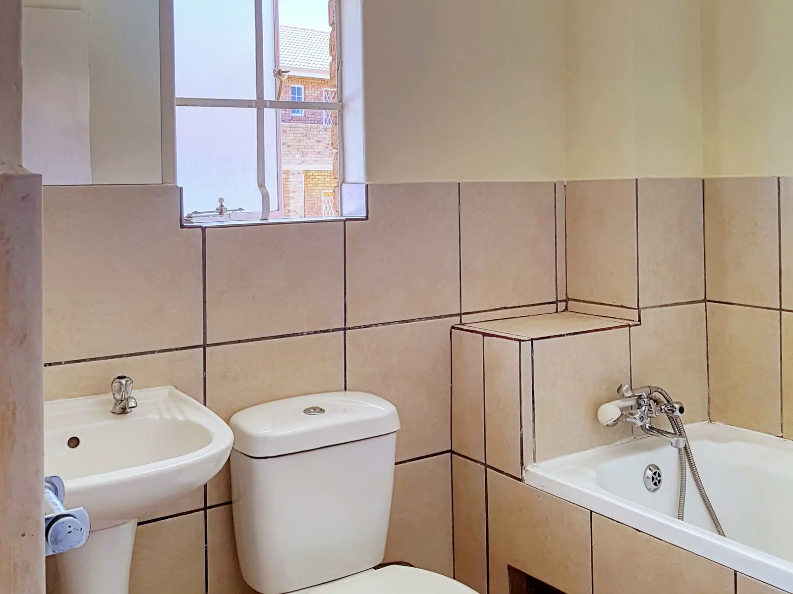 Bathroom 1: wide photo from the far corner. The basin, the toilet and the end of the bath under a small window (sample photo)