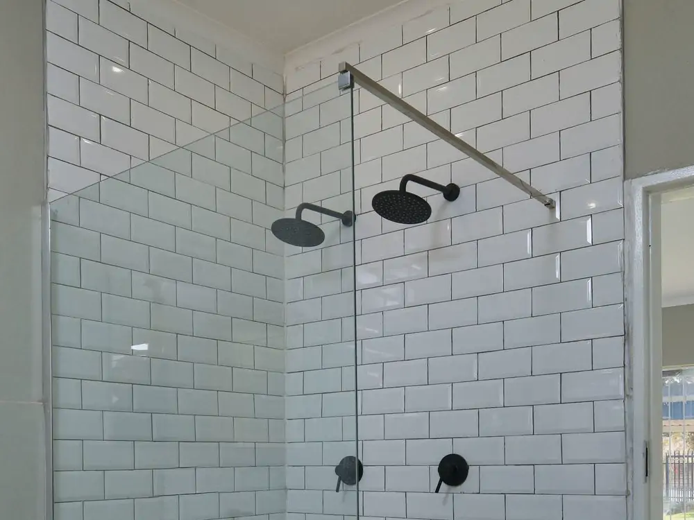 Bathroom 2: the ceiling. The shower heads and the glass screen's top rail against the white tiles (sample photo)