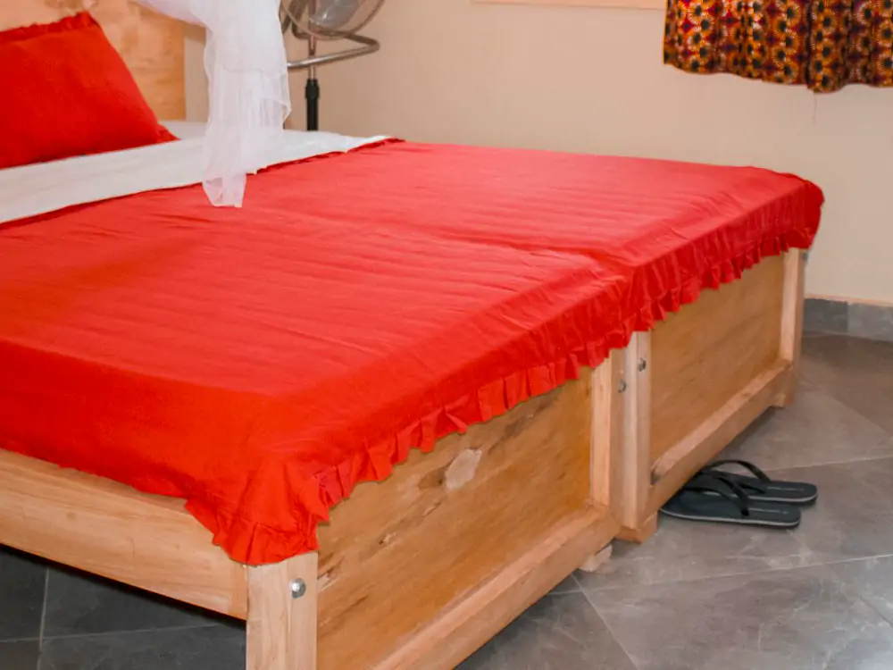 Bedroom 1: the floor. The foot of the bed and the gray floor tiles, with a pair of slippers (sample photo)