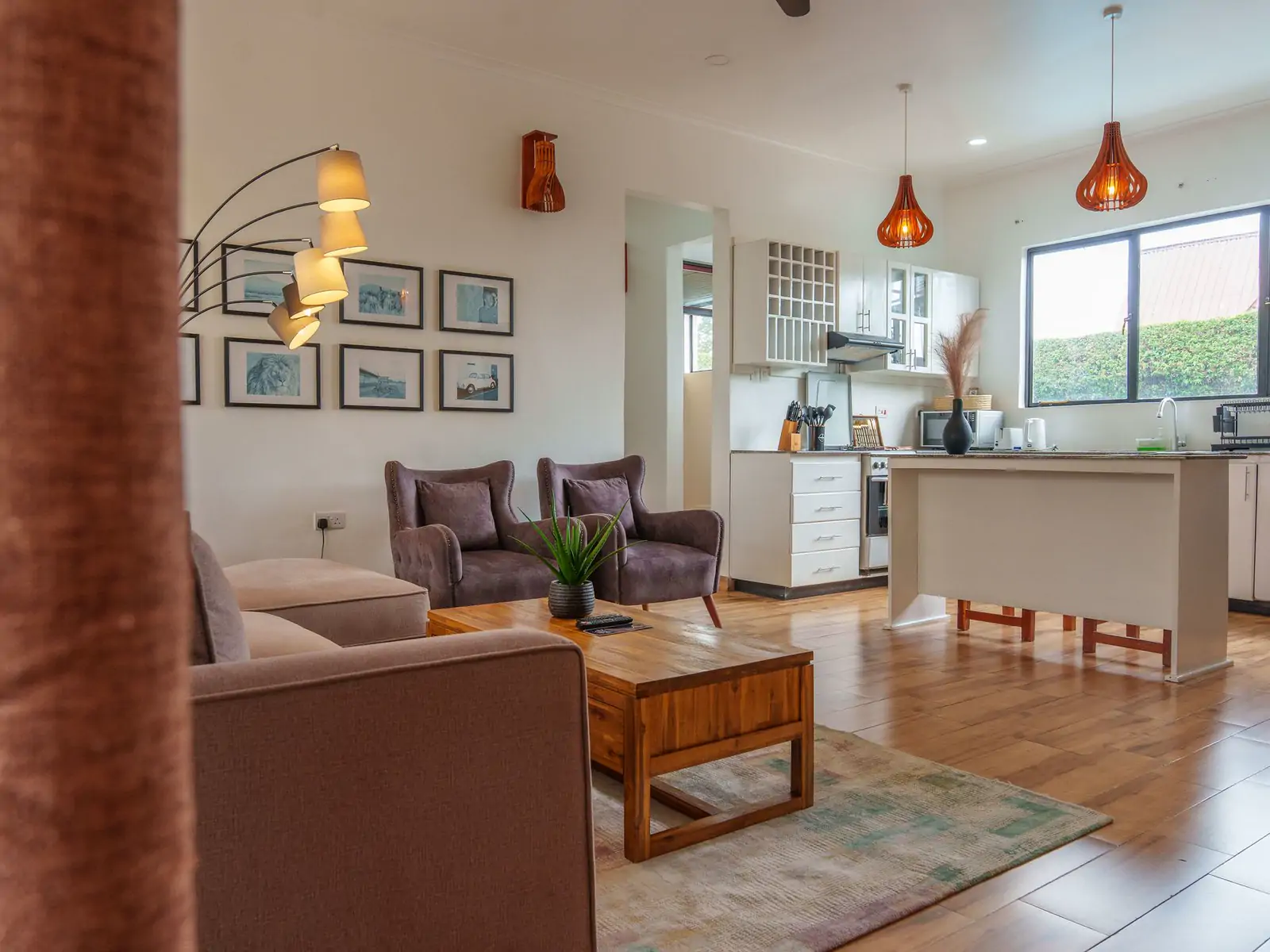 Living or dining room: wide photo from the doorway. A living room with brown armchairs, a sofa and a wooden coffee table, open to the kitchen (sample photo)