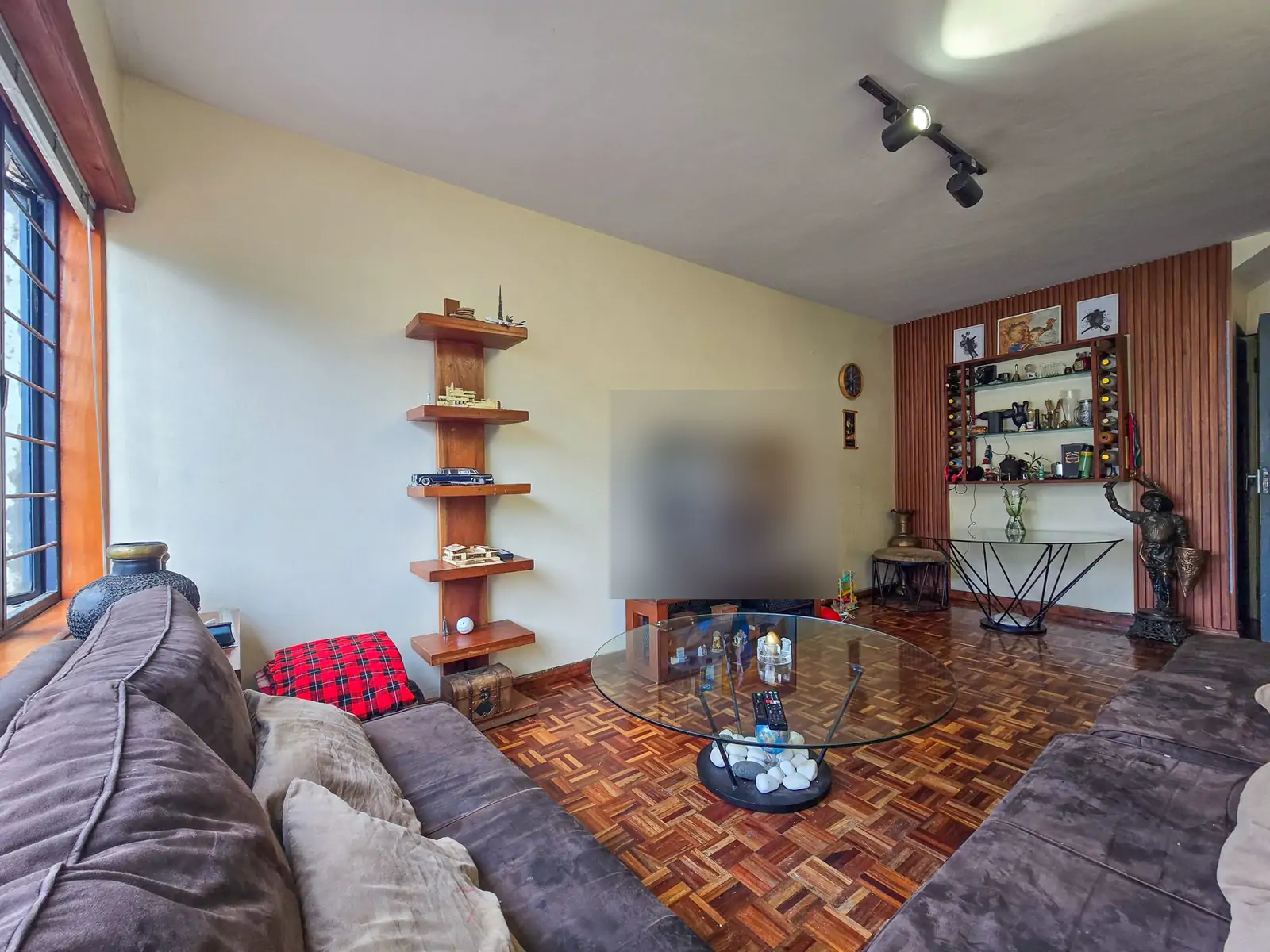 Living or dining room: wide photo from the far corner. A living room with two gray sofas, a glass coffee table, wall shelves and a parquet floor (sample photo)